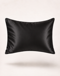 A black satin pillow sham with a subtle sheen, featuring a small debossed brand logo in the upper left corner, shown against a clean off-white background.