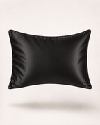 A black satin pillow sham with a subtle sheen, featuring a small debossed brand logo in the upper left corner, shown against a clean off-white background.